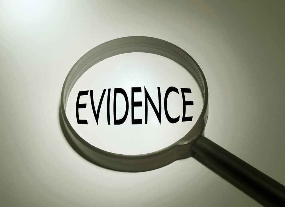 Magnifying glass zooming in on the word 'evidence' .