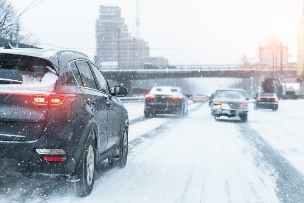 Snow covered city highway, cars navigate slippery Philadelphia roads in winter weather conditions.