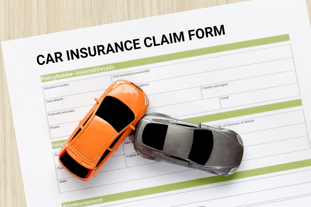 This image portrays a lighthearted and creative way to represent filing a car insurance claim, using toy cars to symbolize the real accident.