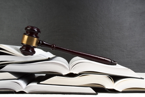 Legal gavel resting on open law books against a dark background, symbolizing law and justice.